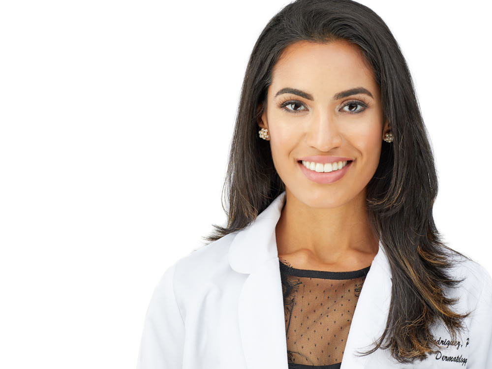Professional headshot of a dermatologist in a white coat on a clean white background