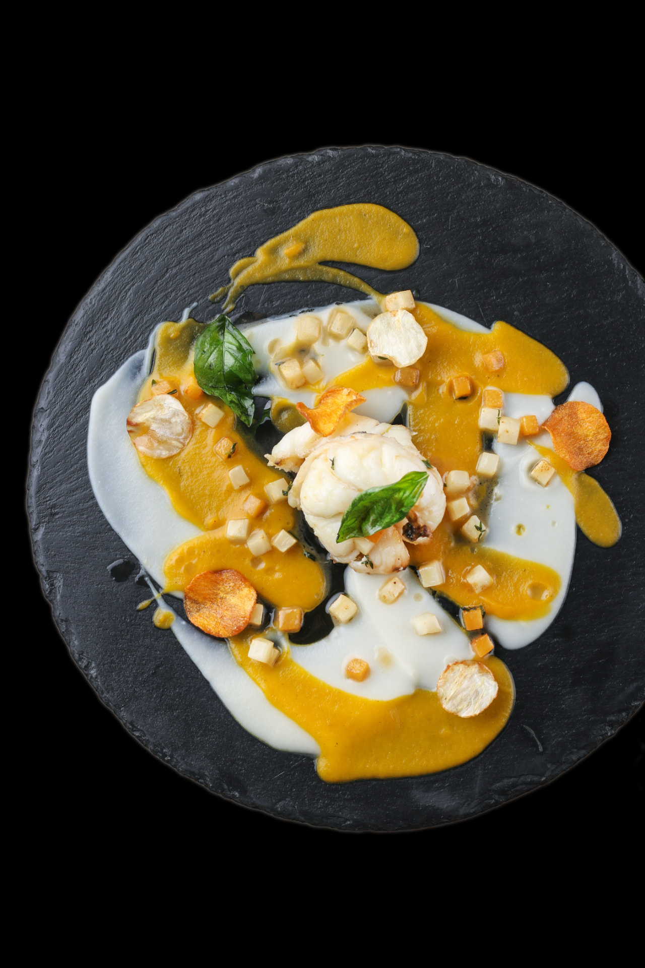 Fine-dining prawn plated on slate with saffron and cream sauces